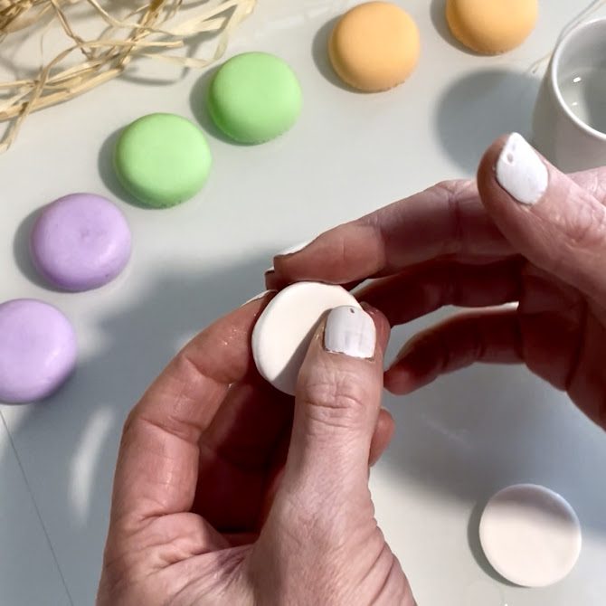 Mains lissant les bords d’un cercle découpé dans la silk clay à l’aide d’un doigt légèrement humidifié pour adoucir les contours.