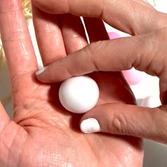 Boule de foam clay blanche lisse et ronde, roulée dans les mains