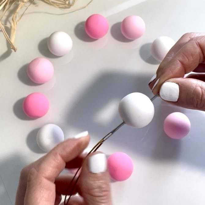 Mains passant une grosse aiguille dans une boule en Foam Clay