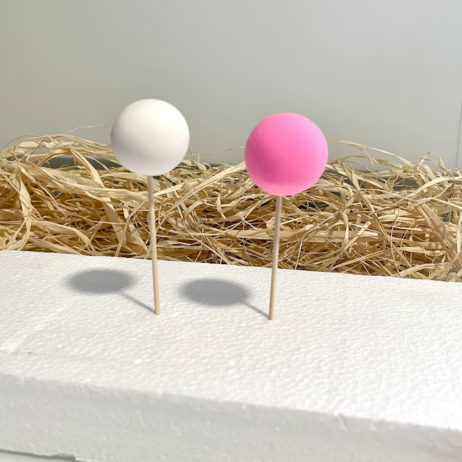 Deux boules de foam clay séchant sur des cure-dents plantés dans un bloc de polystyrène