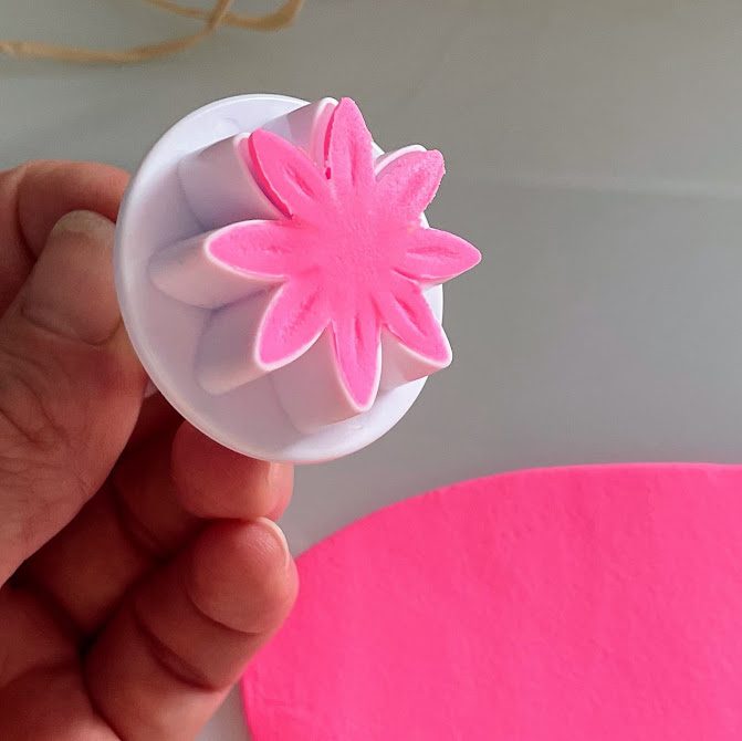 Emporte-pièce retourné, contenant encore la fleur découpée en foam clay rose.