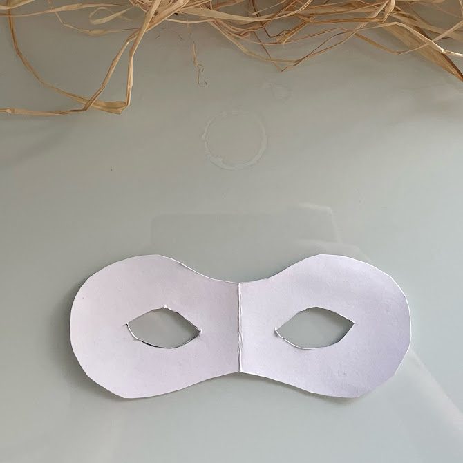 Gabarit de masque de carnaval découpé dans une feuille cartonnée, avec deux ouvertures en amande pour les yeux.