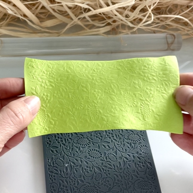 Mains montrant une feuille de mousse EVA embossée de motifs avec la plaque de texture en arriere plan